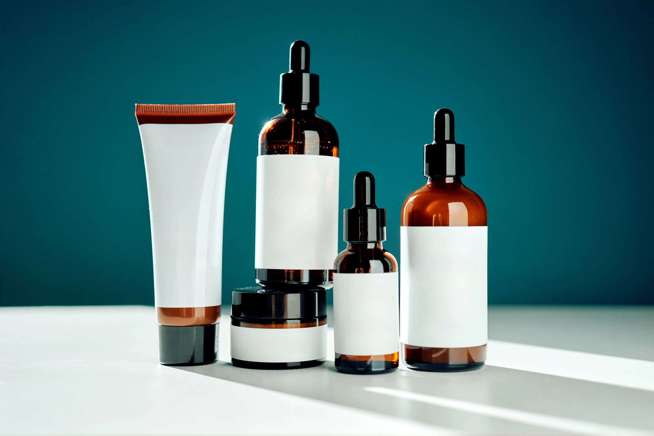 Frascos de cuidado personal en tono ámbar y productos de belleza sobre una superficie limpia